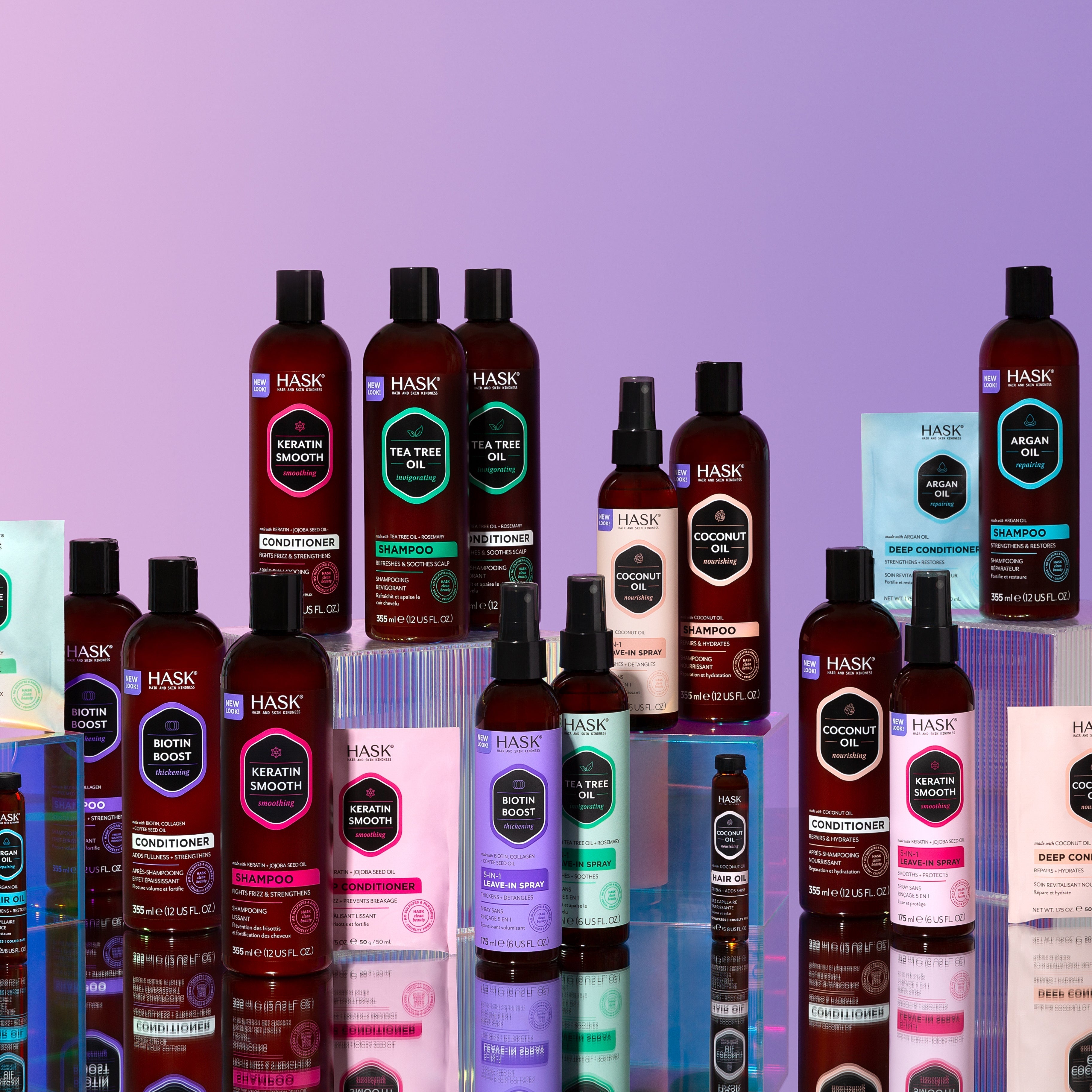 Uitstalling van diverse HASK-haarverzorgingsproducten op gekleurde blokken tegen een paarse achtergrond